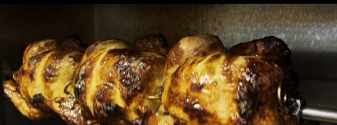 Rotisserie chickens turning over the flame at Golden Shawarma in Richardson