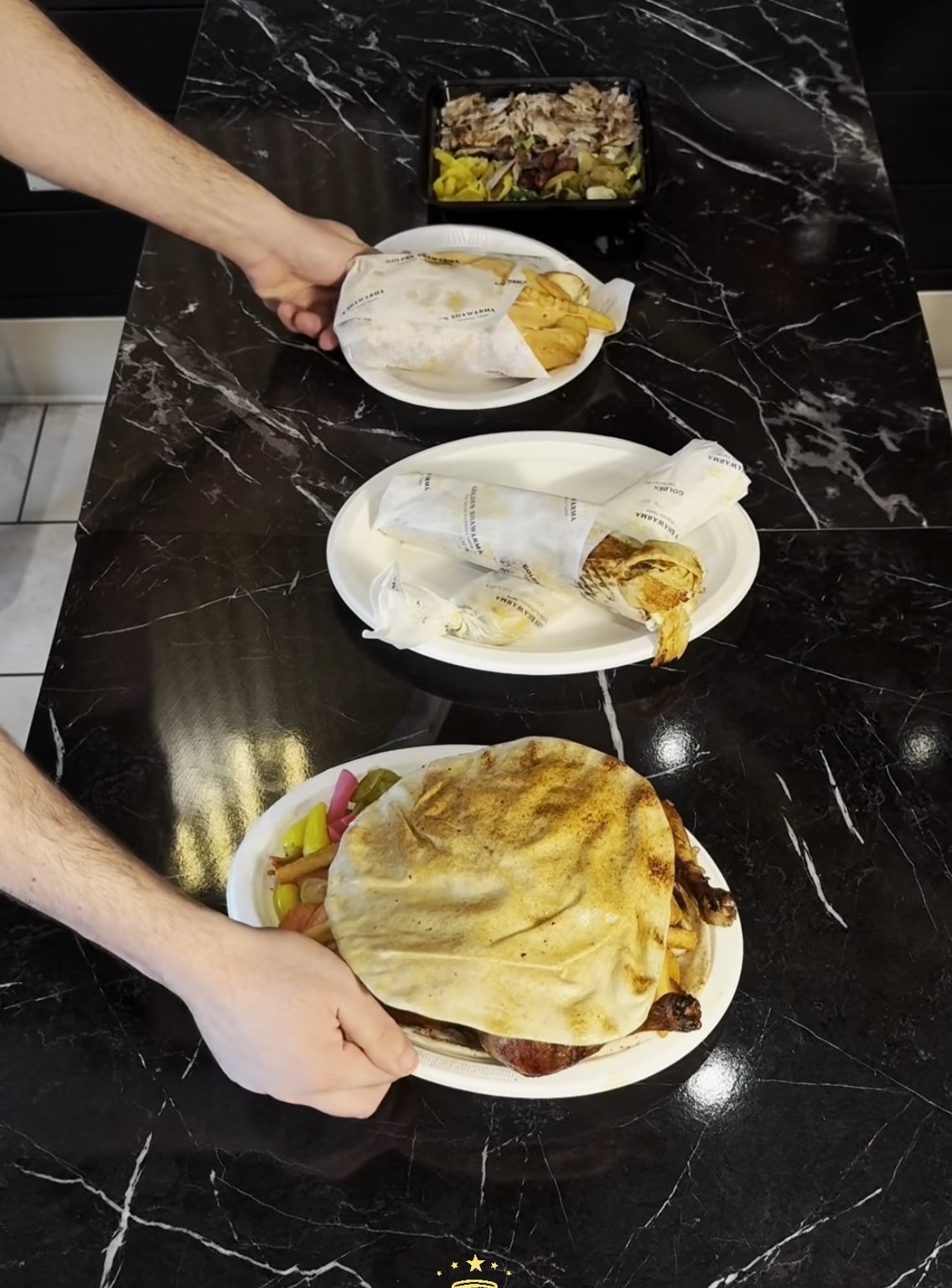 Shawarma wraps and rotisserie chicken plated on black marble at Golden Shawarma